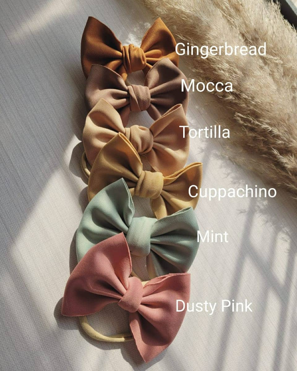 Set of five fabric bows in different colors with labels on a light background