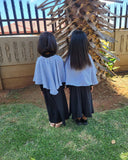 Two people wearing matching abayas standing in front of a decorative wooden structure.