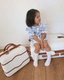 Child sitting on a suitcase with a white background