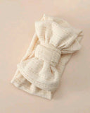 Beige knitted headband with a large bow on a light pink background