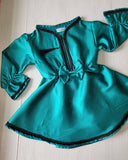Teal dress with black trim on a light wooden floor