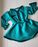 Teal dress with black trim on a white surface