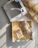 Gift box with beige baby items on a light wooden surface