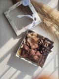 Set of brown hair accessories in a decorative box on a light wooden surface.