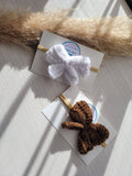Two headbands with white and brown bows on a light wooden surface.