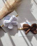 Two headbands with white and brown bows on a light surface.