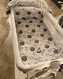 Baby crib with patterned sheet and canopy in a store setting
