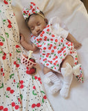 Baby in a cherry-themed outfit lying on a matching blanket