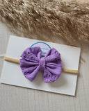 Purple bow headband on a white card with a textured background