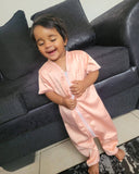 Child in a pink onesie sitting on a dark gray couch