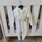 White baby romper with ruffled collar hanging on a crib