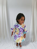 Child wearing a floral dress with purple and yellow flowers on a white background