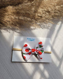 White headband with red cherries design on a white card, placed on a textured surface.