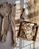 Beige baby onesie, beanie, wooden brush, pacifier clip & pacifier