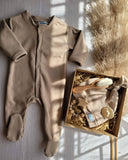 Beige baby onesie, beanie, wooden brush, pacifier clip & pacifier